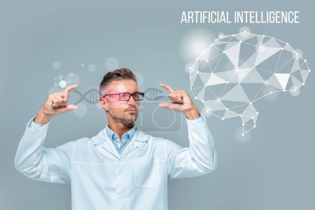 Foto de Guapo científico en gafas que sostienen interfaz médica con ADN y cerebro aislado en gris, concepto de inteligencia artificial - Imagen libre de derechos