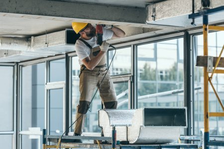 Foto de Constructor en googles de protección y perforación hardhat en el sitio de construcción - Imagen libre de derechos