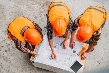 Foto de Vista de ángulo alto del grupo de constructores que discuten el plan de construcción en el sitio de construcción - Imagen libre de derechos