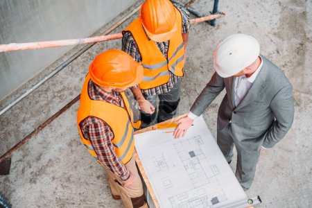 Foto de Vista de ángulo alto de los constructores y el arquitecto discutiendo plano en el sitio de construcción - Imagen libre de derechos