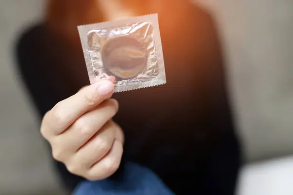 Condom ready to use in female hand, give condom safe sex concept on the bed Prevent infection and Contraceptives control the birth rate or safe prophylactic. World AIDS Day, Leave space for text.