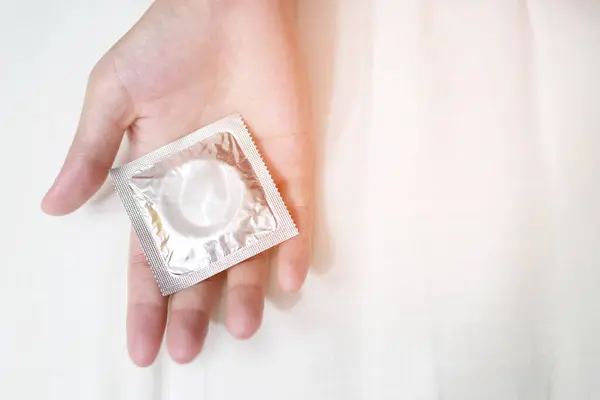 Condom ready to use in female hand, give condom safe sex concept on the bed Prevent infection and Contraceptives control the birth rate or safe prophylactic. World AIDS Day, Leave space for text.