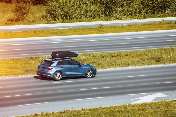 Urban Escape: Family Car with Rooftop Box Hits the Road