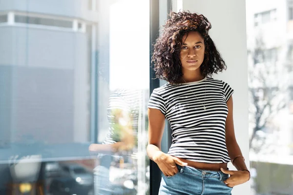 Welcome to my safe space. Cropped portrait of an attractive young woman standing alone and posing against the window in her home