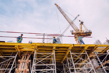 Foto de 17 enero 2023, Dubai, Emiratos Árabes Unidos: Trabajadores con cascos en una obra de construcción con maquinaria de grúa - Imagen libre de derechos