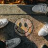 people standing around a smiley face on the sidewalk