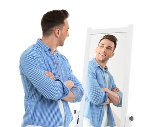 Photo of Young man looking at himself in mirror on white background