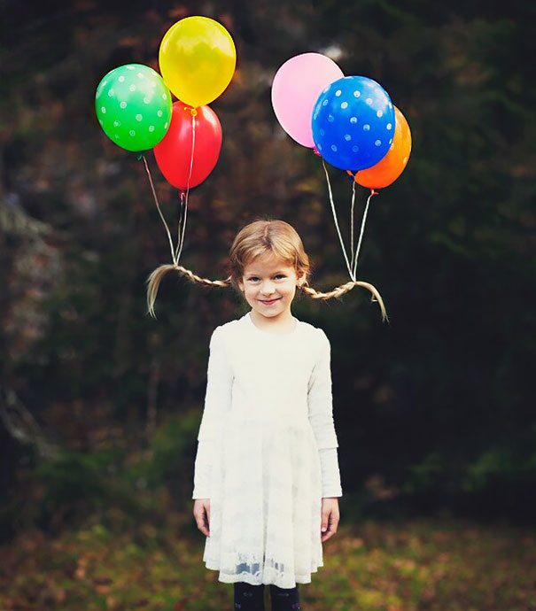 Girl with creative hairdo tied to colorful balloons for Crazy Hair Day.