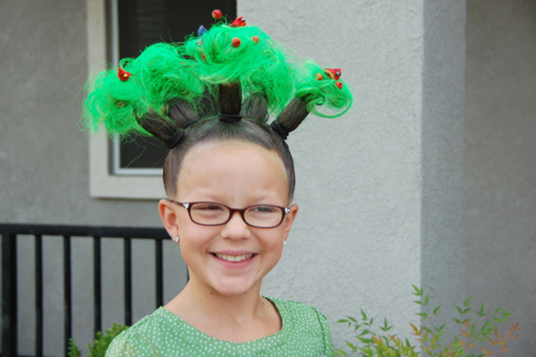 Child with green, creative hairstyle on Crazy Hair Day, smiling outdoors.