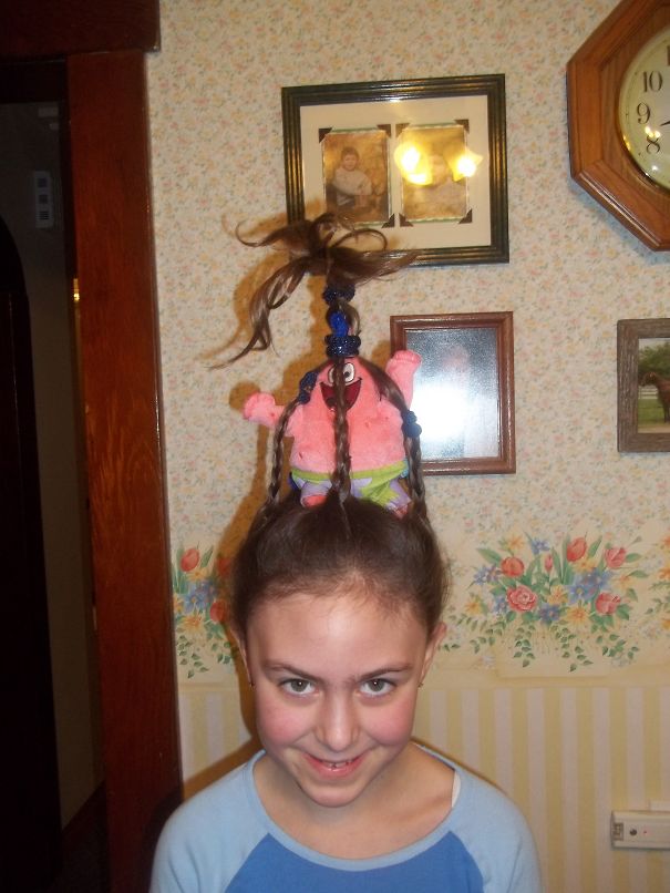 Girl with a crazy hair day style featuring a character plush tied into her braids, standing in a vintage-decor room.