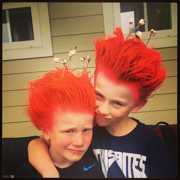 Two boys with vibrant orange spiked hairstyles and flower accents, showcasing a crazy hair day look.