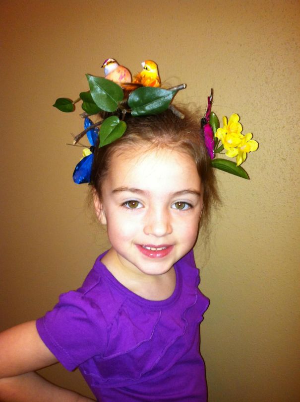 Child with a creative Crazy Hair Day style, featuring birds and leaves in her hair, wearing a purple shirt.