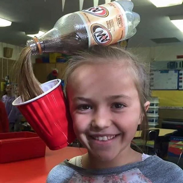 Girl with a creative hairdo resembling a soda bottle pouring into a cup, participating in Crazy Hair Day.