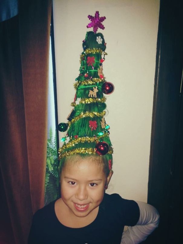 Child with hair styled like a Christmas tree, decorated with ornaments and tinsel for Crazy Hair Day.