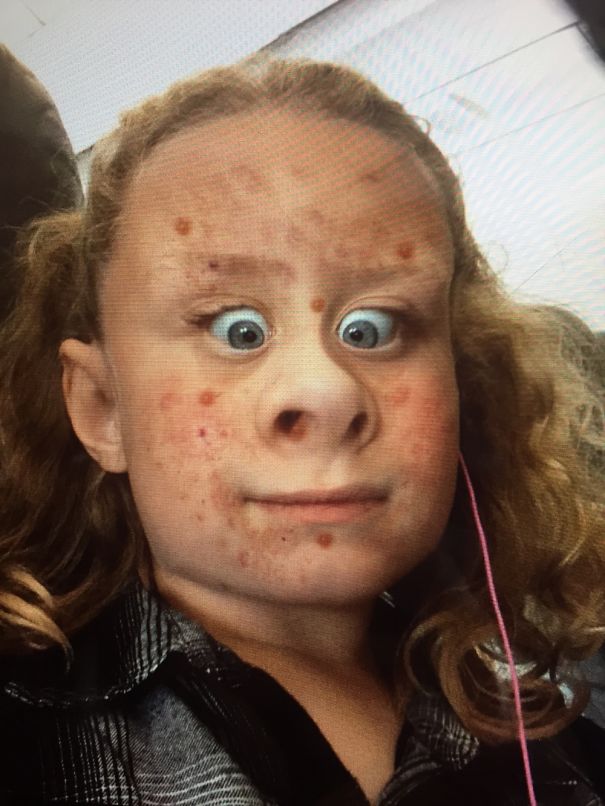 Child with a funny, exaggerated facial expression for Crazy Hair Day, with curled blond hair and plaid shirt.