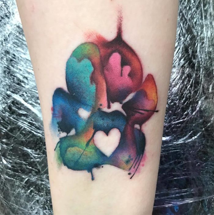 Colorful dog paw print tattoo on arm with heart design.