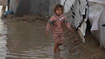 A child walks carefully through puddles caused by heavy rain, Deir al-Balah, Gaza, 23.01.2025