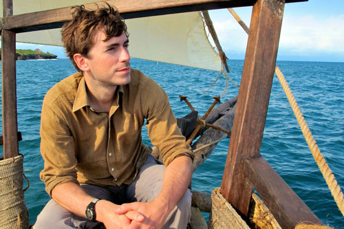 Simon Reeve in a boat on the Indian Ocean surrounded by blue water and blue sky 