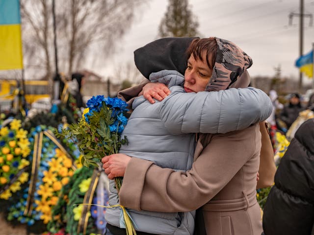 <p>Tetiana, whose son died fighting in Bakhmut a few weeks ago, is hugged and comforted by a friend as they mark the one year anniversary of Russia’s invasion of Ukraine</p>