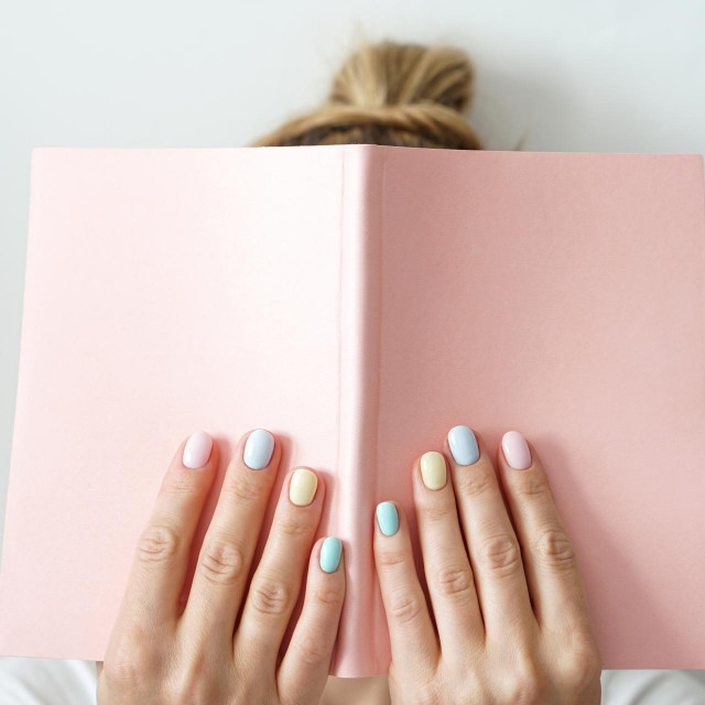 Stylish trendy color female manicure. Womanâ€™s hands keep pink note pad