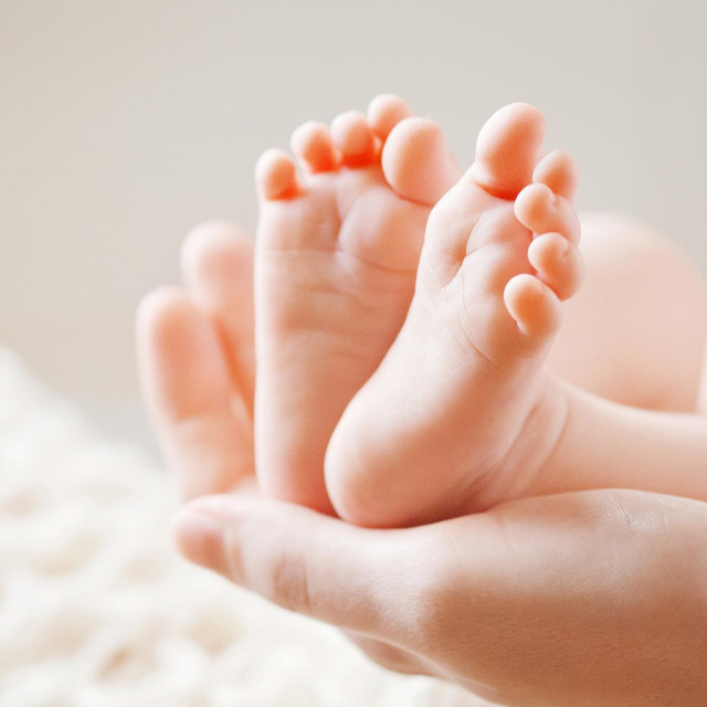 Baby feet in mother hands. Mom and her Child. Happy Family concept. Beautiful conceptual image of Maternity