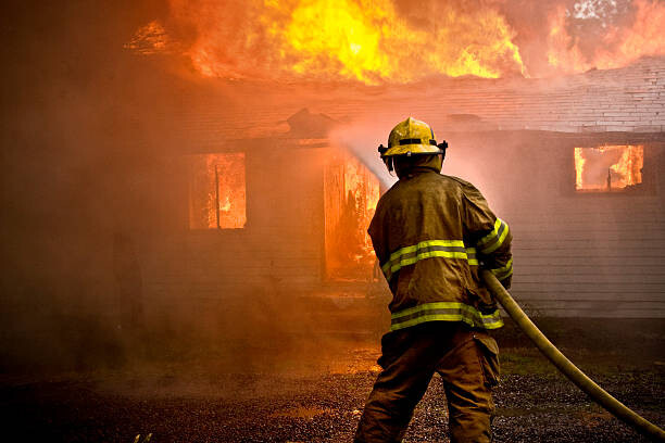 Fotografi Firefighter spraying water at a house fire