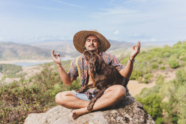 Fotografia young man meditating in nature with his dog.