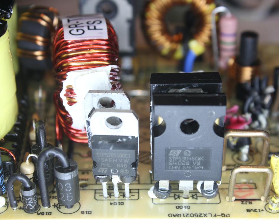 Closeup of the output diodes. At the left are cylindrical diodes mounted vertically. In the middle are pairs of rectangular power Schottky diodes; each package holds two diodes. These diodes were attached to a heat sink for cooling. At right note the two staple-shaped copper wires used as current-sensing resistors.