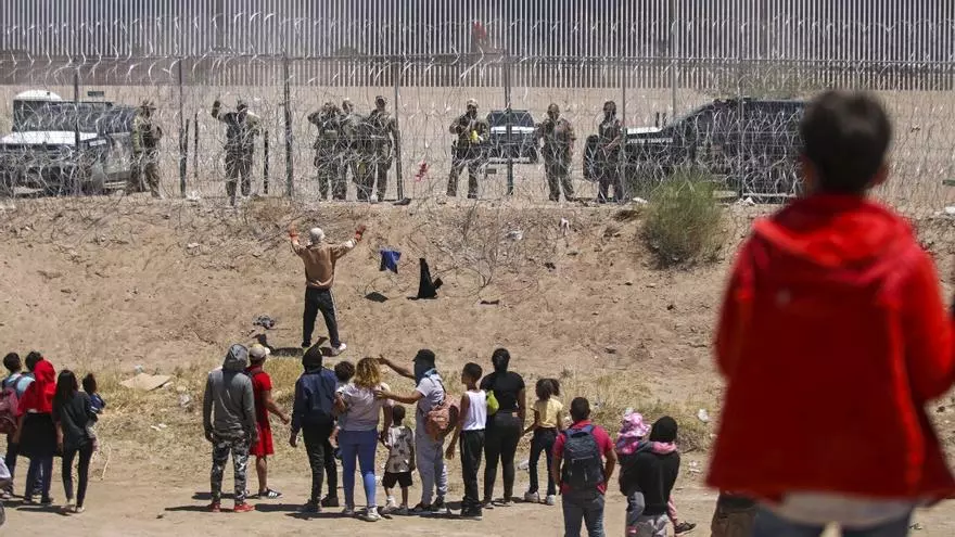 Foto ilustrativa. Migrantes esperan detrás de la valla de ciclón en la frontera entre México y Estados Unidos