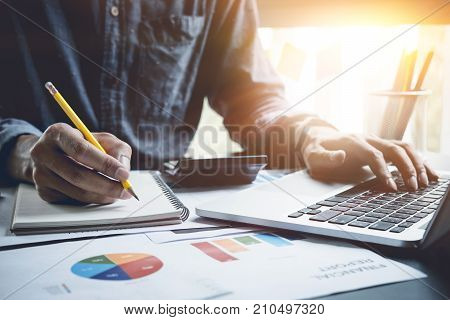 A Man Analysis Business Document With Laptop Computer Counting With Cost And Writing Make Note At Of