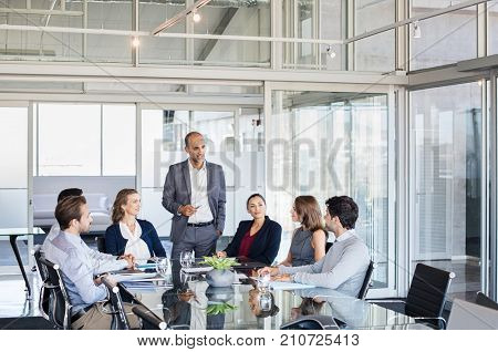 Human resource manager training people about company and future prospects. Group of businesspeople sitting in meeting room and listening to the speaker. Leader man and work group in a conference room.