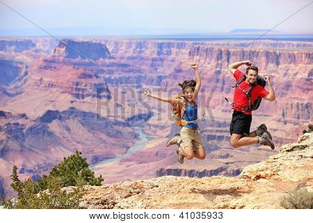 Happy people jumping in Grand Canyon. Young multiethnic couple on hiking travel. Grand Canyon, south rim, Arizona, USA.