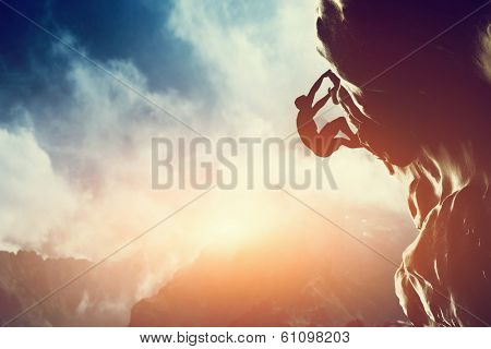 A silhouette of man climbing on rock, mountain at sunset. Adrenaline, strenght, ambition