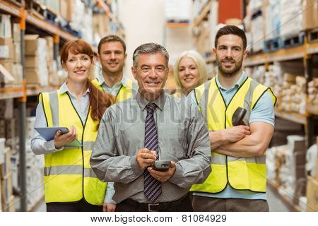 Smiling warehouse team with arms crossed in a large warehouse