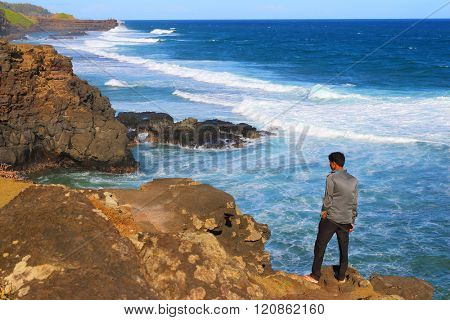 GRIS-GRIS, MAURITIUS ISLAND - 1. NOVEMBER, 2015: Unidentified tourist on sea cliff where the constant squashing of waves against the flanks of the cliff gives the impression that the cliff is crying.