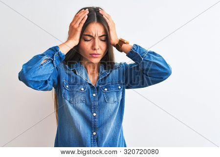 Young beautiful woman wearing casual denim shirt standing over isolated white background suffering from headache desperate and stressed because pain and migraine. Hands on head.