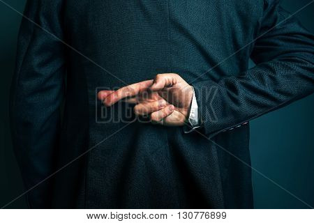 Dishonest businessman telling lies lying businessperson holding fingers crossed behind his back