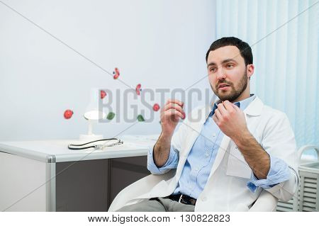 Friendly male medicine therapeutist doctor sitting in office, talking to patient and looking in camera. Medical help, physician reception or insurance concept. Physician waiting for patient.