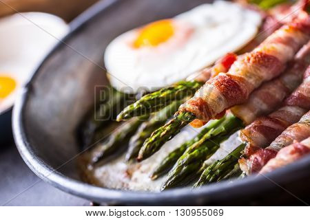 Asparagus. Asparagus and roll bacon. Grilled asparagus with rolled bacon and fried egg. Fried old pan full of rolled bacon with green asparagus and fried egg.