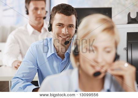 Young customer service operator talking on headset, smiling.