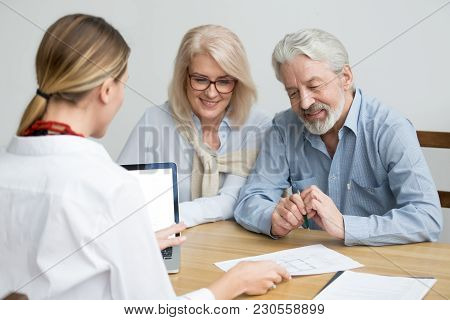 Real Estate Agent Showing House Plan To Aged Couple, Realtor Making Property For Sale Offer To Senio