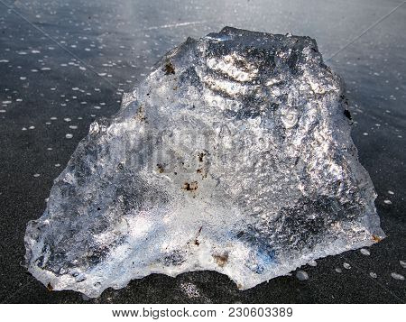 Charming Winter Sun Hiden Behind Pice Of Clear Ice. Shining Piece Of Ice Lies On Lake Ice And Create