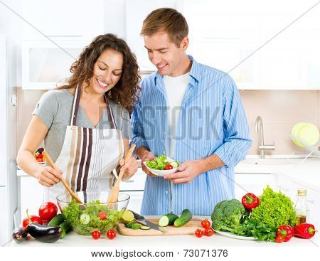 Happy Couple Cooking Together - Man and Woman in their Kitchen at home Preparing Dinner - Vegetable Salad. Diet. Dieting. Healthy vegetarian food, vegan. Family cooking together at home