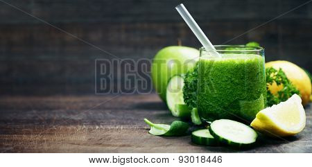 Fresh organic green smoothie with spinach, cucumber, parsley, celery and lemon on wooden background