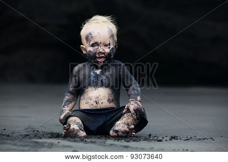 Portrait Of Dirty Child On The Black San Beach