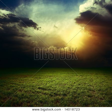 Storm dark clouds over field with grass