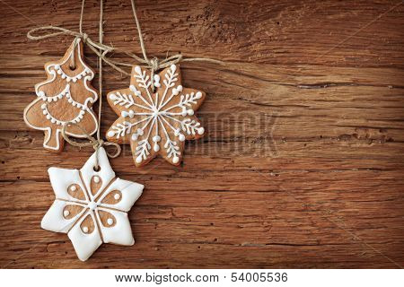 Gingerbread cookies hanging over wooden background