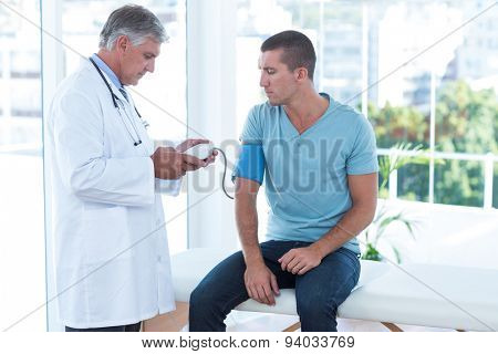 Doctor examining his patients blood pressure in medical office