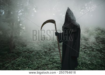 Death with a scythe in the dark misty forest