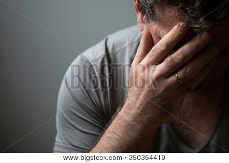 Unhappy sad man in depression covered his face with his hand